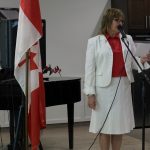 A lady dressed festively for Canada Day speaks into a microphone