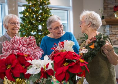 Three ladies mingling while sorting through the Christmas wreaths and decorating