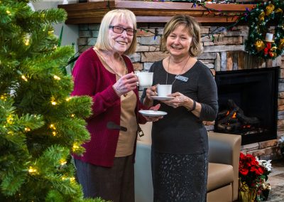 Two ladies enjoying a cup of hot cocoa near the fireplace