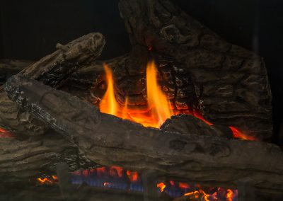 A lit fireplace burns some logs