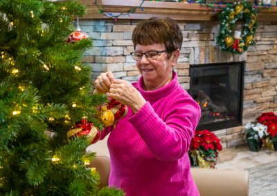 A lady places decorations on the branches of the Christmas tree