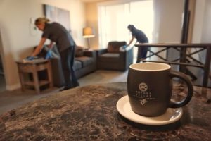 A Rotary Villas coffee mug sits in focus while two ladies clean a suite