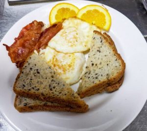 Bacon, eggs, and toast with a couple orange slices.