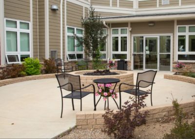 A patio table and chairs sit facing the firepit on one of Rotary Villas' patios.
